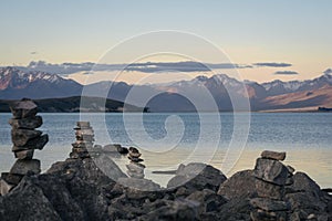 Stones balancing in Lake Tekapo with beautiful view of southern alps behind. New Zealand