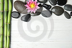 Stones, bamboo, lotus flower and space for text on wooden background, flat lay. Zen lifestyle