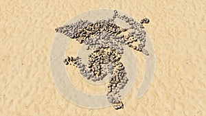 Stones on beach sand handmade symbol shape, golden sandy background, baby Cupid with an arrow sign.