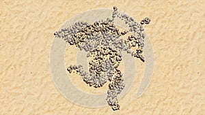 Stones on beach sand handmade symbol shape, golden sandy background, baby Cupid with an arrow sign