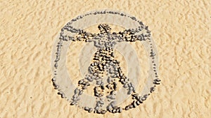 Stones on beach sand handmade symbol shape, golden sandy background, sign of vitruvius man