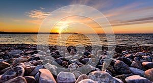 Stones on a beach with sunset on the ocean sea.