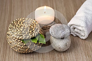 Stones, a candle, a jar and green leaves, a white rolled towel. Spa setting concept