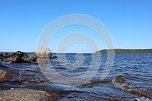 Stones granite coast of finish lake on bright sunny summer day blue sky and water landscape
