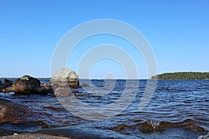 Stones granite coast of finish lake on bright sunny summer day blue sky and water landscape