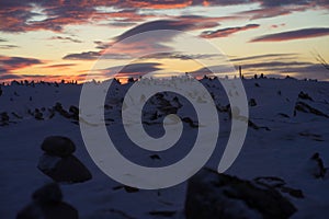 stones are heaped in the snow near the road at dawn