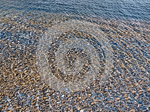 Stones on the lake bottom with sunshine reflection on the water