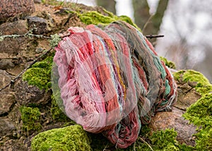 Stones overgrown with green moss, colored wool yarn skeins, handicraft concept, hand knitting, autumn time, handicrafts