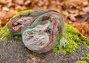 Stones overgrown with green moss, colored wool yarn skeins, handicraft concept, hand knitting, autumn time, handicrafts