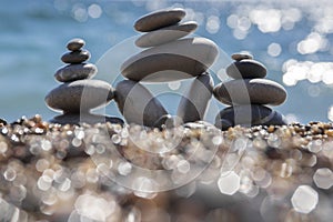 Stones and pebbles stack, harmony and balance, three stone cairns on seacoast with ocean waves on background