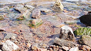 Stones and pebbles in water. sea waves approaching the rocky shore slow motion. water surface with ripples