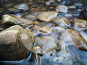Stones protrude from the water in a small hilly stream photo