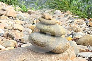 Stones pyramid near small river symbolizing zen