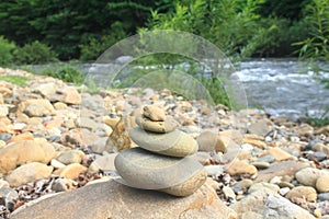 Stones pyramid near small river symbolizing zen