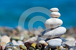 Stones pyramid on pebble beach with blur sea background. Travel and relax concept