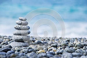 Stones pyramid on pebble beach symbolizing spa concept with blur sea background