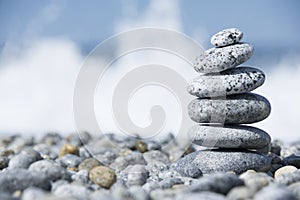 Stones pyramid on pebble beach symbolizing spa concept with blur sea background