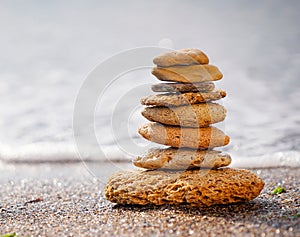 Stones pyramid on sand symbolizing zen, harmony, balance. Ocean in the background. Soft focus