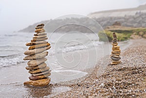 Stones pyramid on sand symbolizing zen, harmony, balance. Ocean in the background. Soft focus