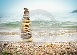 Stones pyramid on sand symbolizing zen, harmony, balance. Ocean in the background. Soft focus