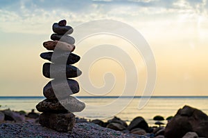 Stones pyramid on the seashore. Sunset on pebble beach. Balanced life, relax.