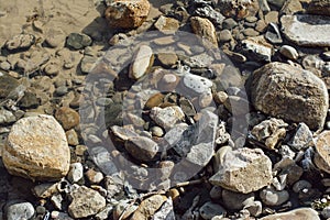 Stones and rocks in brown, gray and black on the shore of Ondina beach