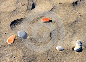 Stones on sand at beach. Sea stones background at seashore. Colored stone on coastline.