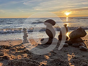 Stones on sea shore, sunset time. Play with stones, building towers. Zen peace hobby during vacations.