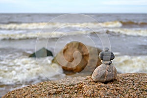 Stones are stacked in a pyramid against the background of the sea. A pyramid of small stones on the beach. The concept