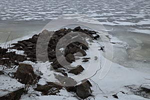 Stones surrounded by ice of frozen river