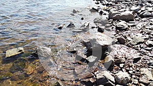 Stones in transparent water. sea waves approaching the rocky shore. water surface with ripples