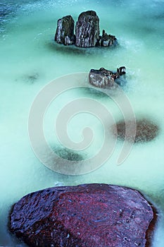Stones and wooden pales in frozen river