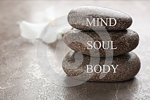 Stones with words MIND, BODY, SOUL on brown marble background, space for text. Zen lifestyle