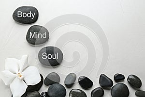 Stones with words MIND, BODY, SOUL on light background, top view and space for text. Zen lifestyle