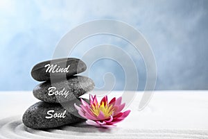 Stones with words Mind, Body, Soul and lotus flower on sand. Zen garden