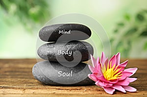 Stones with words Mind, Body, Soul and lotus flower on table. Zen lifestyle