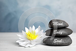 Stones with words Mind, Body, Soul and lotus flower on wooden table. Zen lifestyle