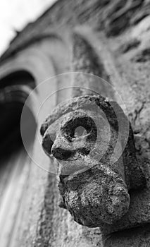 Stonework gargoyle in the shape of a kings head seen at the entrance to an old church.