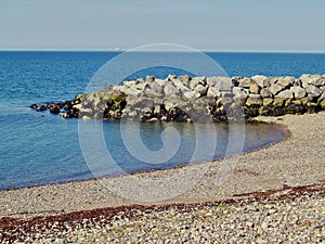 Stony bay with stone built wall with large blocks of rock and sea in background