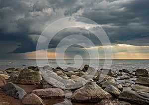 Stony beach by the sea. dramatic sky with sun rays