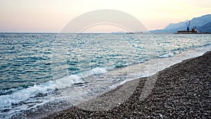 Stony beach and sea waves at sunset light in evening time, Turkey