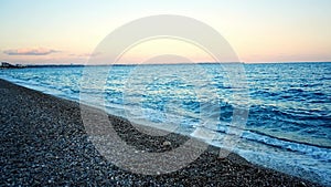 Stony beach and sea waves at sunset light in evening time, Turkey