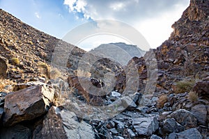 Stony, dry riverbed wadi with remains of raw ore of copper, green stones and rocks, Copper Hike Trail, Hatta, UAE