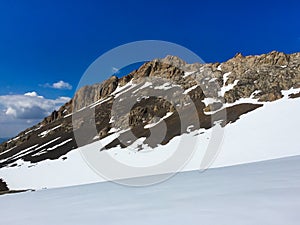 A stony mountain range that rises above the snowy plain.