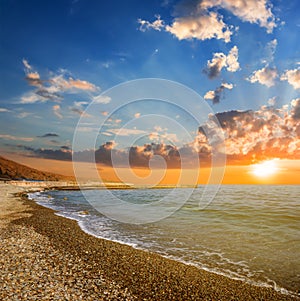 Stony sea beach at the dramatic sunset