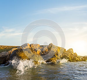 Stony sea coast with waves at the sunset