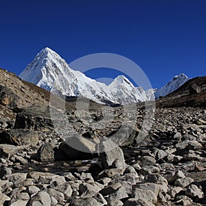 Stony trail of the Everest Base Camp Trek and snow covered Mount Pumori