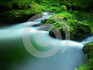 Stony weir on small mountain river. Stream is flowing over square blocks and makes milky water.