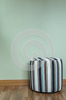 Stool in empty room against a green wall