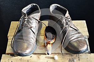 On a stool are leather shoes and a brush to clean them.